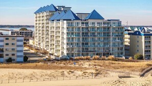 Un hôtel à plusieurs étages, doté d’un toit bleu, situé près d’une plage de sable.