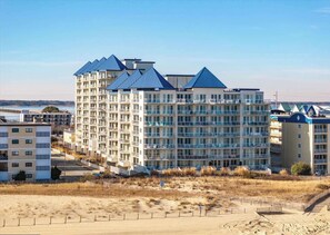 Ein mehrstöckiges Hotel mit blauem Dach in Strandnähe, mit sandigem Untergrund.