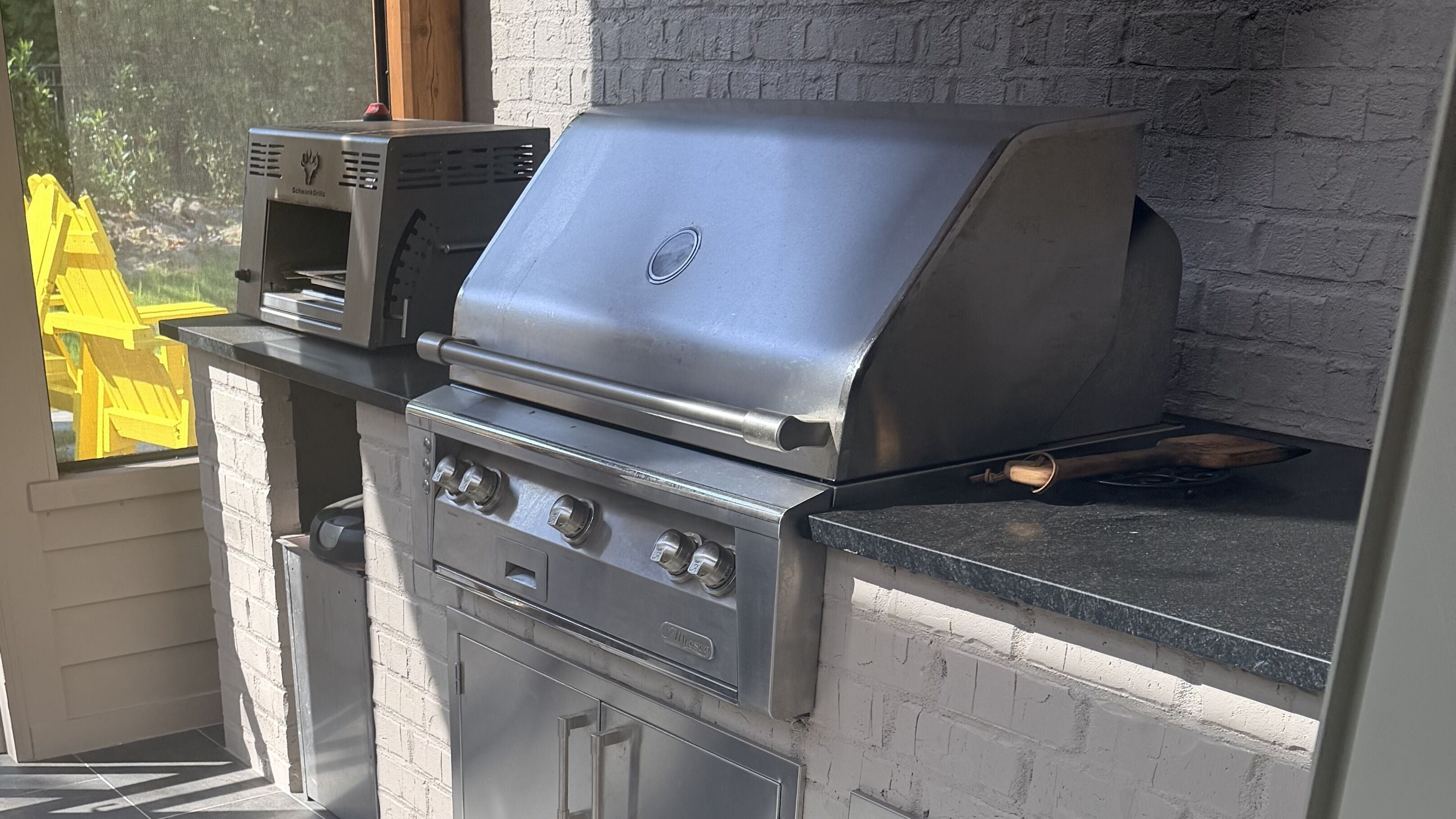 Eine Außenküche mit Grill, Kochfeld und integriertem Backofen.