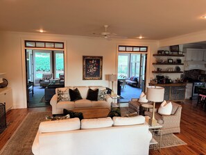 A spacious living area with a sofa, a coffee table, and a dining area visible through an open door.