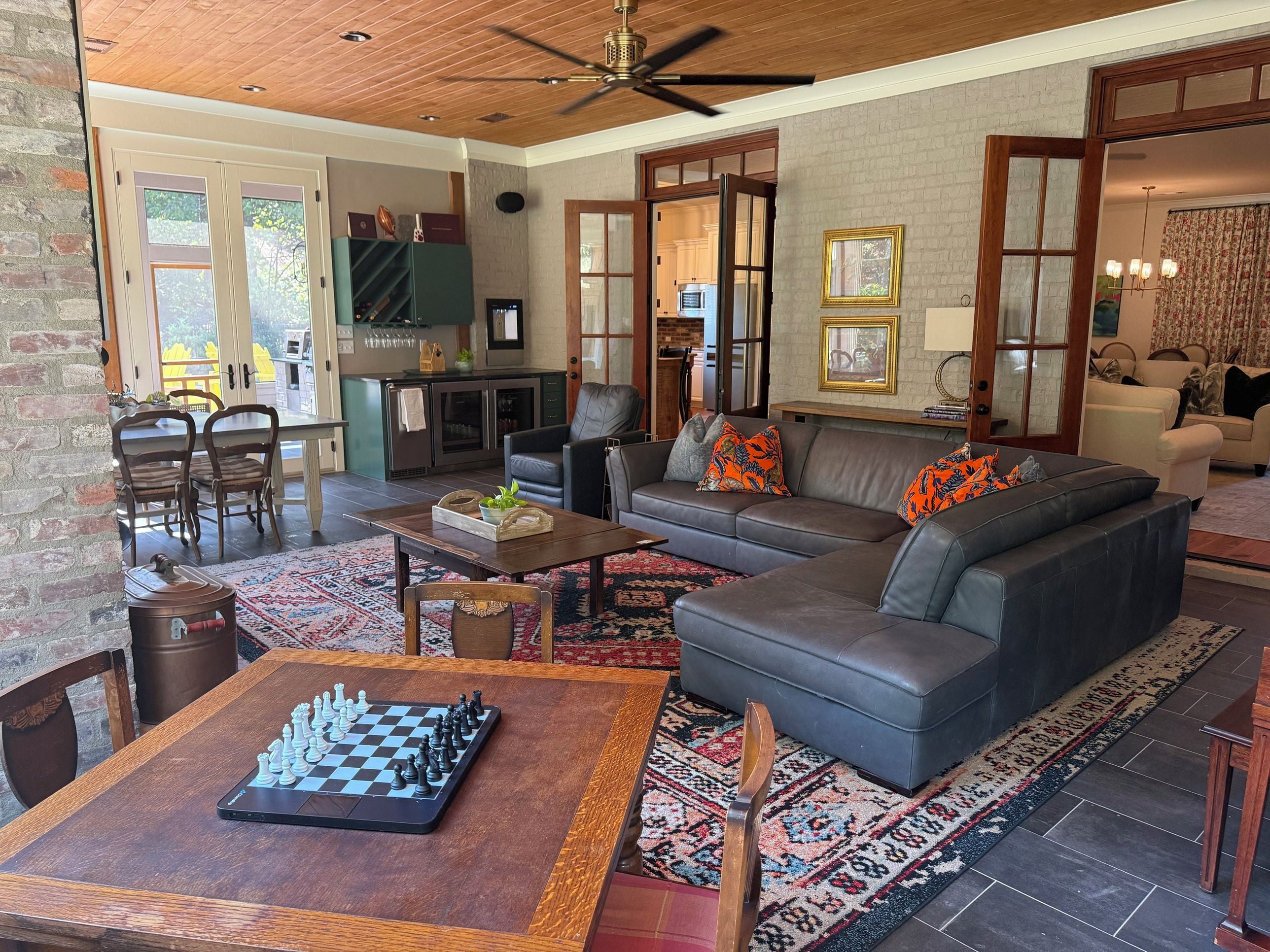 A spacious living area with a sofa, a chess table, and a kitchen in the background.