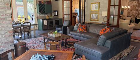 A spacious living area with a sofa, a chess table, and a kitchen in the background.