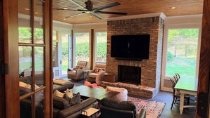 A spacious living room with a fireplace, comfortable seating, and a large TV. - Grand Oaks 6BR by Country Club - Sleeps 12 + Crib - Sauna, Pizza Oven, Ole Miss (Oxford)