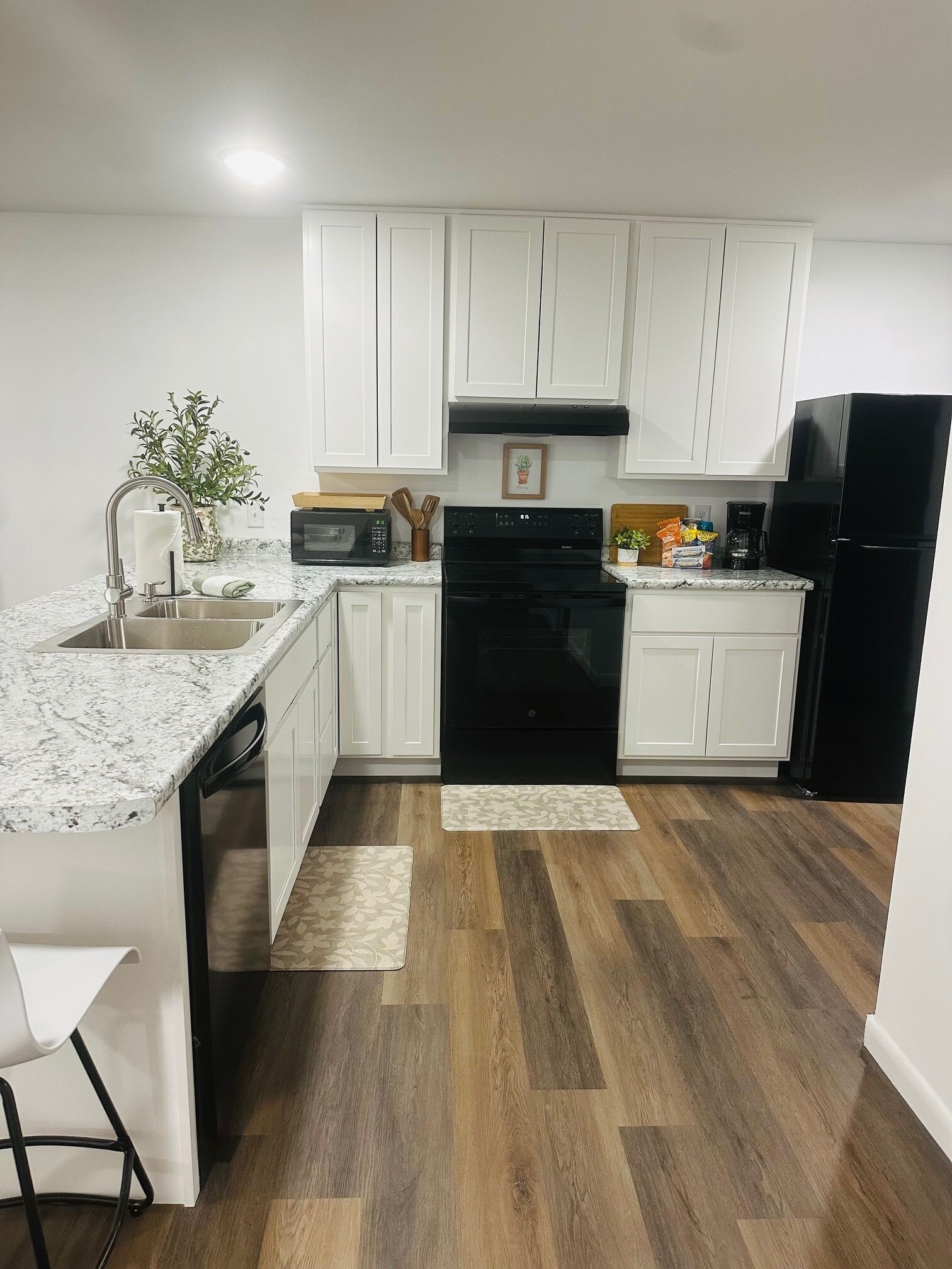 A modern kitchen with white cabinets, a black stove, and a black refrigerator.