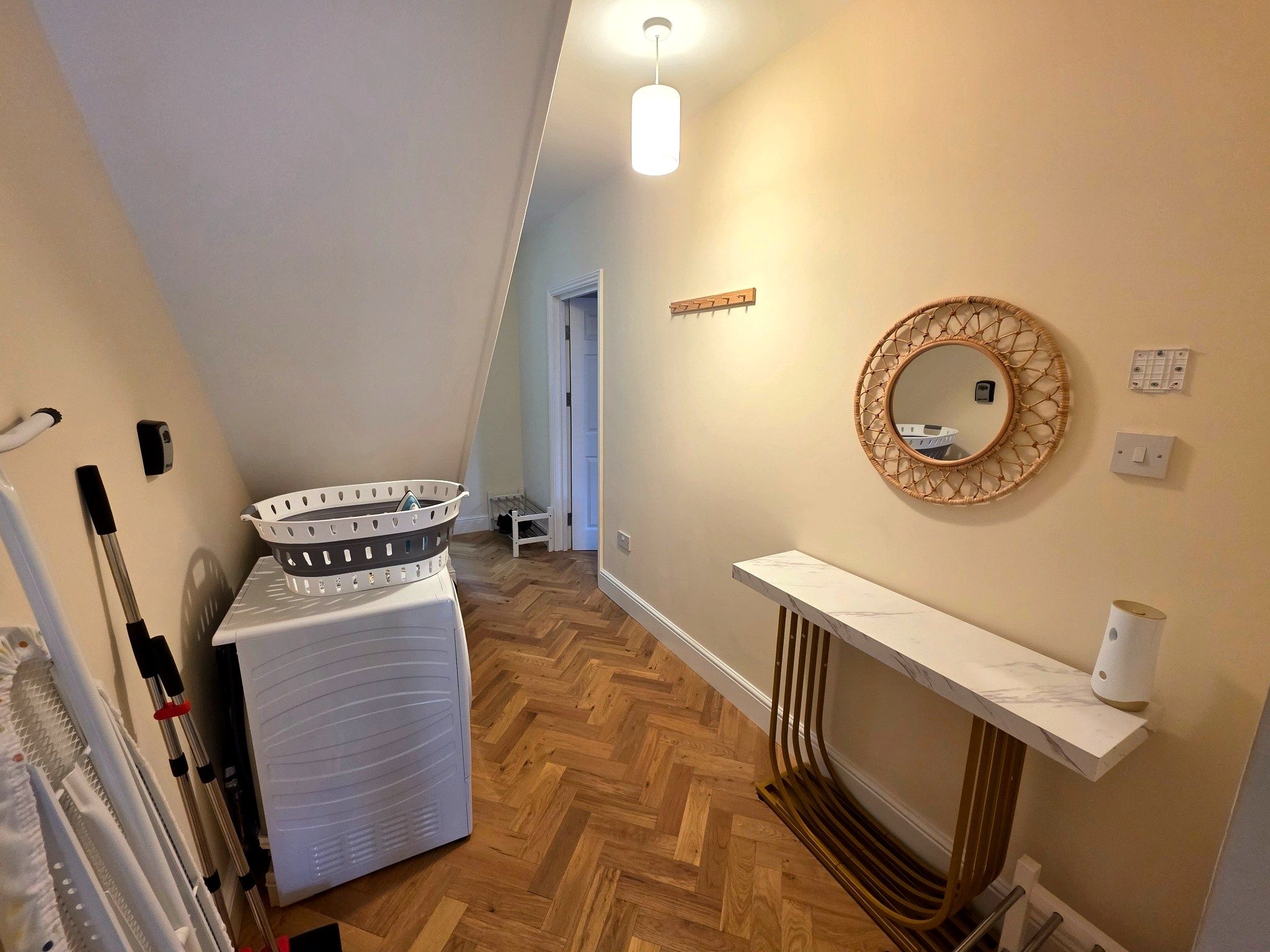 A laundry area with a washing machine, a drying rack, and a ceiling light.