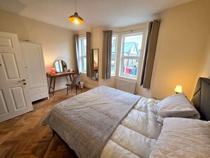 A bedroom with a bed, a desk, a chair, a window with curtains, and a radiator. - Spacious 5BDR Home in Walthamstow Village (Greater London)