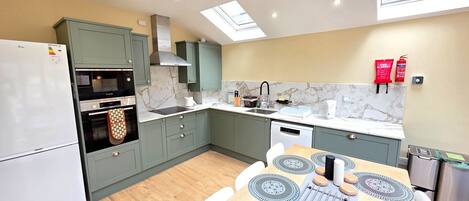 A modern kitchen with a built-in oven, microwave, and a dining area with a round table and chairs.