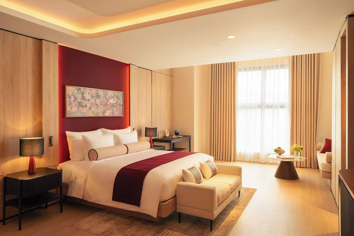 Een moderne hotelkamer met een groot bed, een bank, een bureau en een raam met gordijnen.