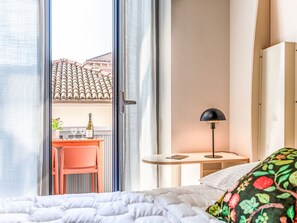 A hotel room with a bed, a desk, a chair, a lamp, and a view of the outside. - Domus Talenti by Interhome (Alba)