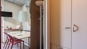 Een moderne keuken met een eethoek, rode stoelen, een witte tafel en een kast met lades.