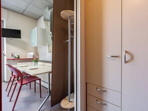 A modern kitchen with a dining area, red chairs, a white table, and a cabinet with drawers. - Domus Talenti by Interhome (Alba)