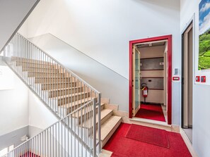 A hotel lobby with a staircase, a red carpeted entrance, and a fire extinguisher. - Domus Talenti by Interhome (Alba)