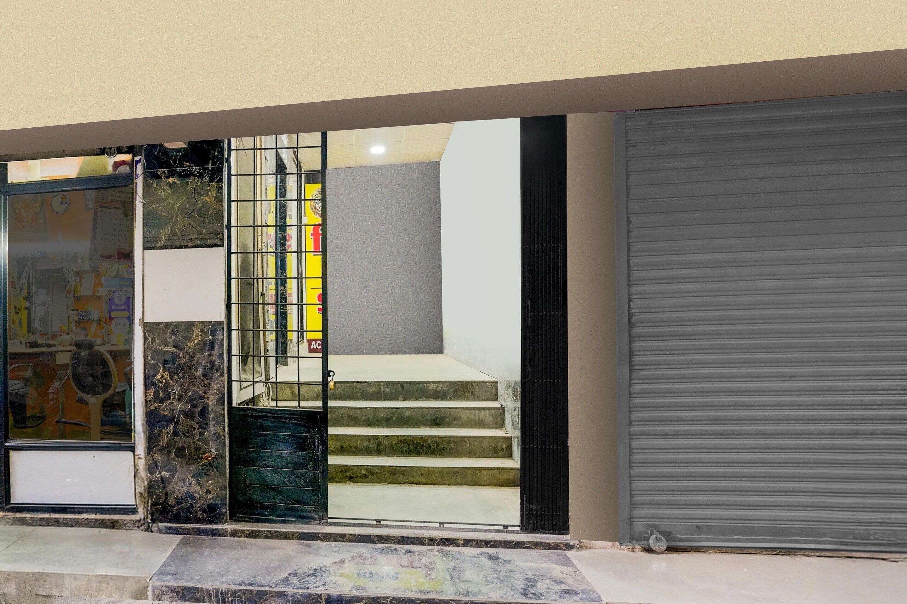 A building entrance with a glass door, a metal gate, and a closed roller shutter.