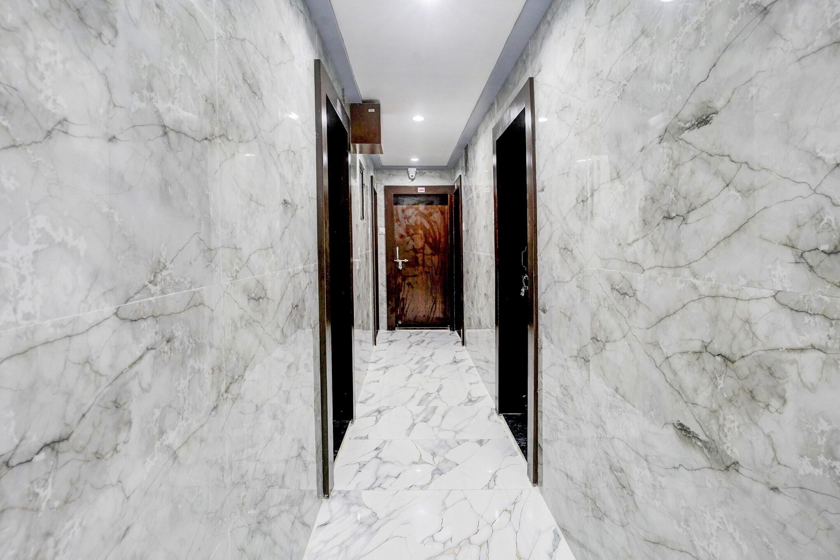 A marble-floored hallway with doors on either side, leading to rooms.