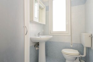 A bathroom with a white sink, a toilet, and a mirror above the sink. - Lignano Sabbiadoro Flat With Parking (Lignano Sabbiadoro)