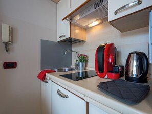 A compact kitchenette with a sink, a red coffee maker, a kettle, and a small potted plant. - Domus Talenti by Interhome (Alba)