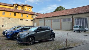 Pysäköintialue, jossa on ketjulla lukittu auto, laatoitettu katto ja kirkas taivas.