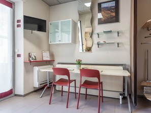 A modern room with a desk, two red chairs, a flat-screen TV, a cabinet, and a mirror. - Domus Talenti by Interhome (Alba)