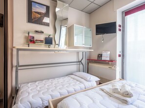 A hotel room with a bed, a desk with a computer, a television, and a window with blinds. - Domus Talenti by Interhome (Alba)