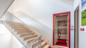 A hotel lobby with a staircase, a red carpeted entrance, and a fire extinguisher. - Domus Talenti by Interhome (Alba)