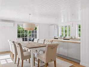 Eine moderne Küche mit weißen Schränken, einem Holztisch und einem großen Fenster.