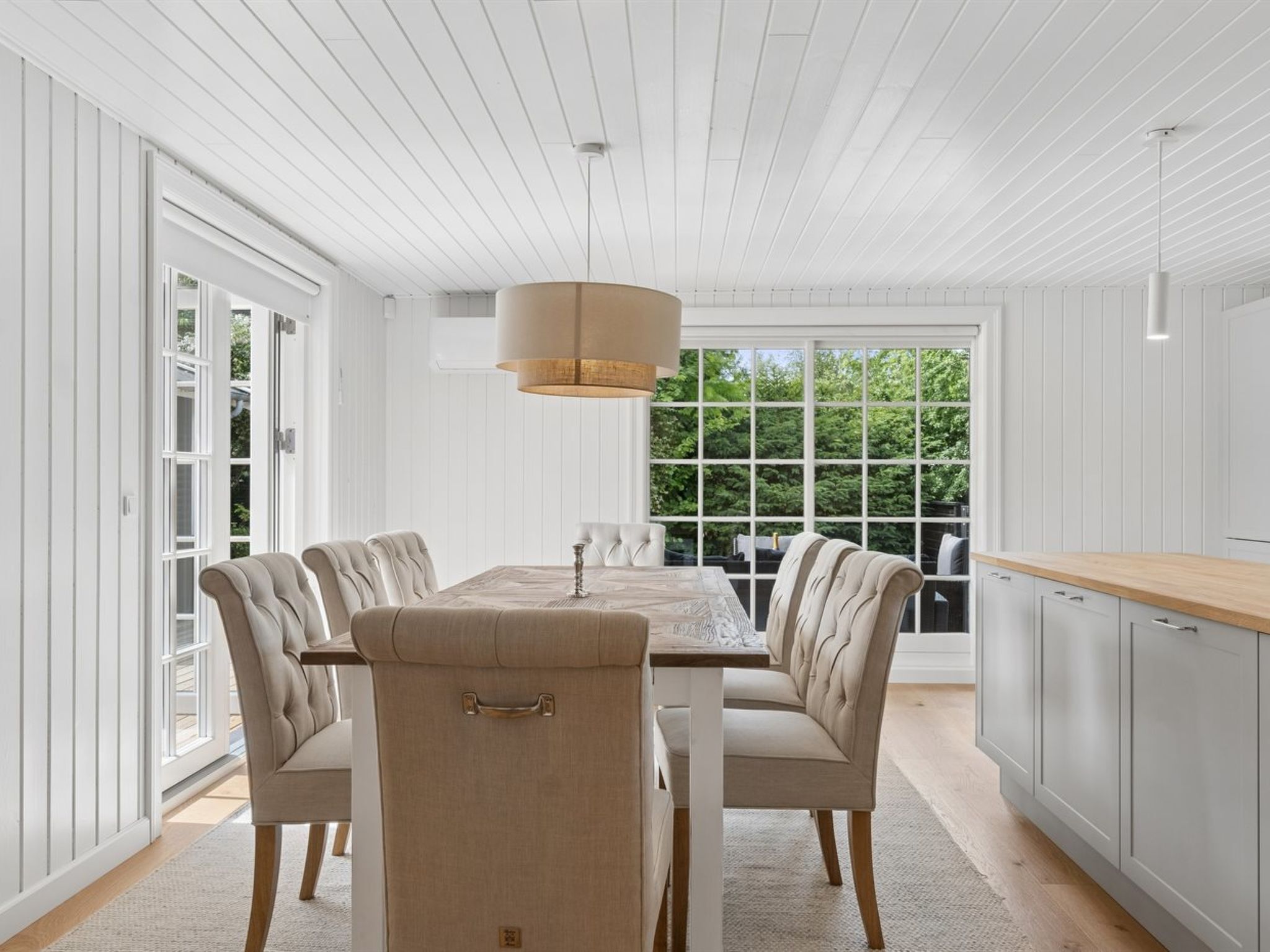 Une salle à manger avec une longue table, six chaises et un luminaire suspendu.