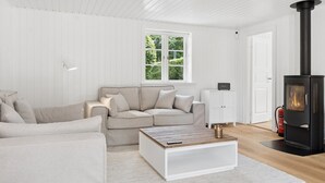 A modern living room with a sofa, a coffee table, a fireplace, and a window with a view of greenery. - "Har" - 685m from the sea by Interhome (Hornbæk)