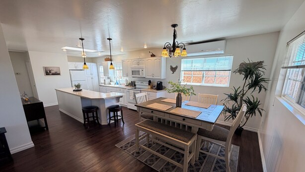 A spacious kitchen with a central island, pendant lighting, and a dining area with a bench.