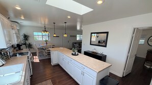 A modern kitchen with white cabinetry, a central island, pendant lighting, and a skylight.