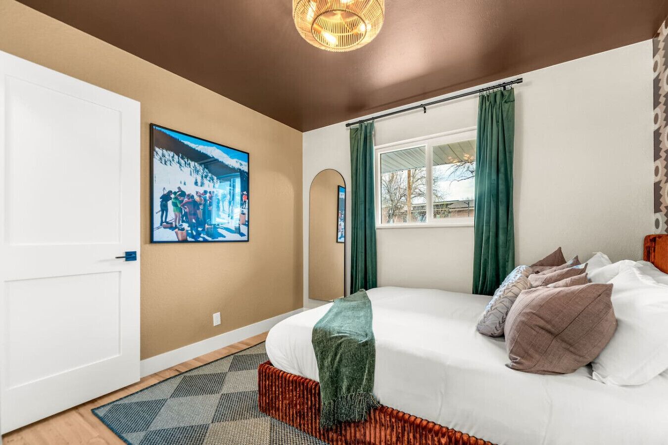 Une chambre à coucher avec un lit, une fenêtre avec des rideaux, une porte et un tableau accroché au mur.