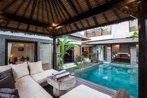 A poolside area with a sofa, a small table, and a thatched roof structure. - Huge Private Pool Villa Atala Canggu Seminyak 4BR (Kerobokan)
