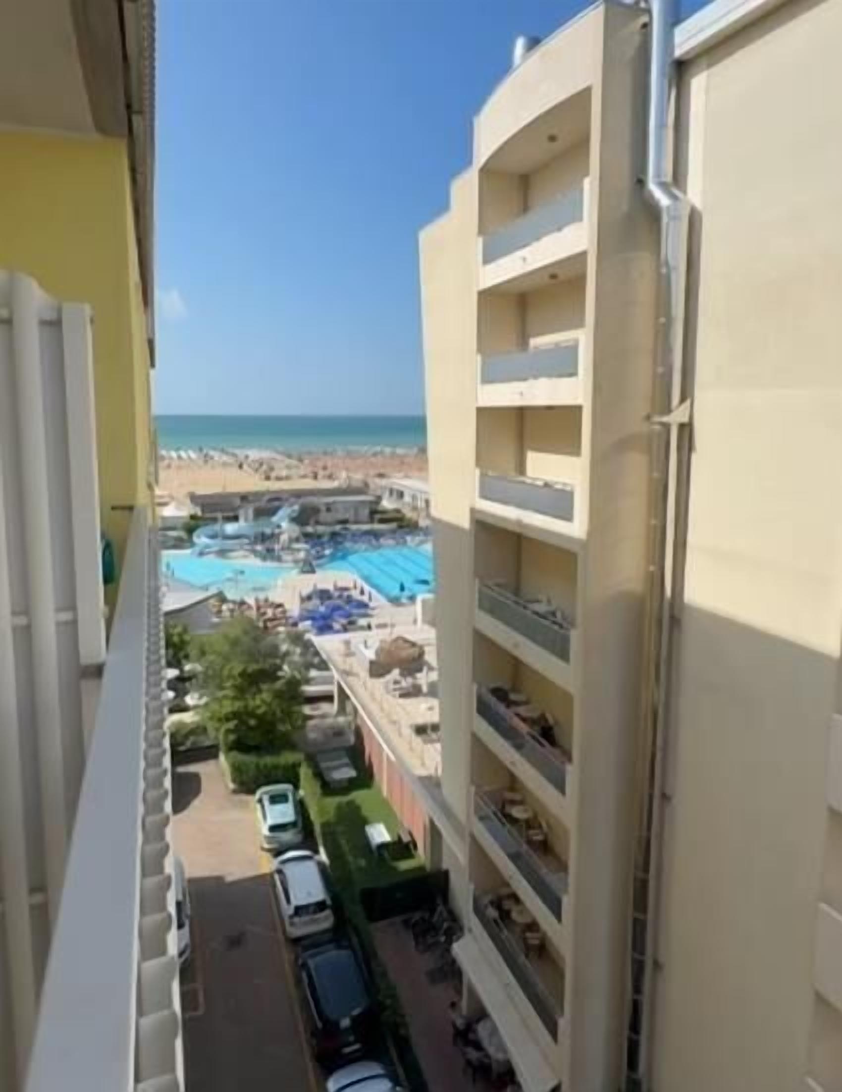 Ein Hochhaus mit mehreren Balkonen mit Blick auf einen Strand und einen Poolbereich.