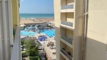 Ein Hochhaus mit mehreren Balkonen mit Blick auf einen Strand und einen Poolbereich.