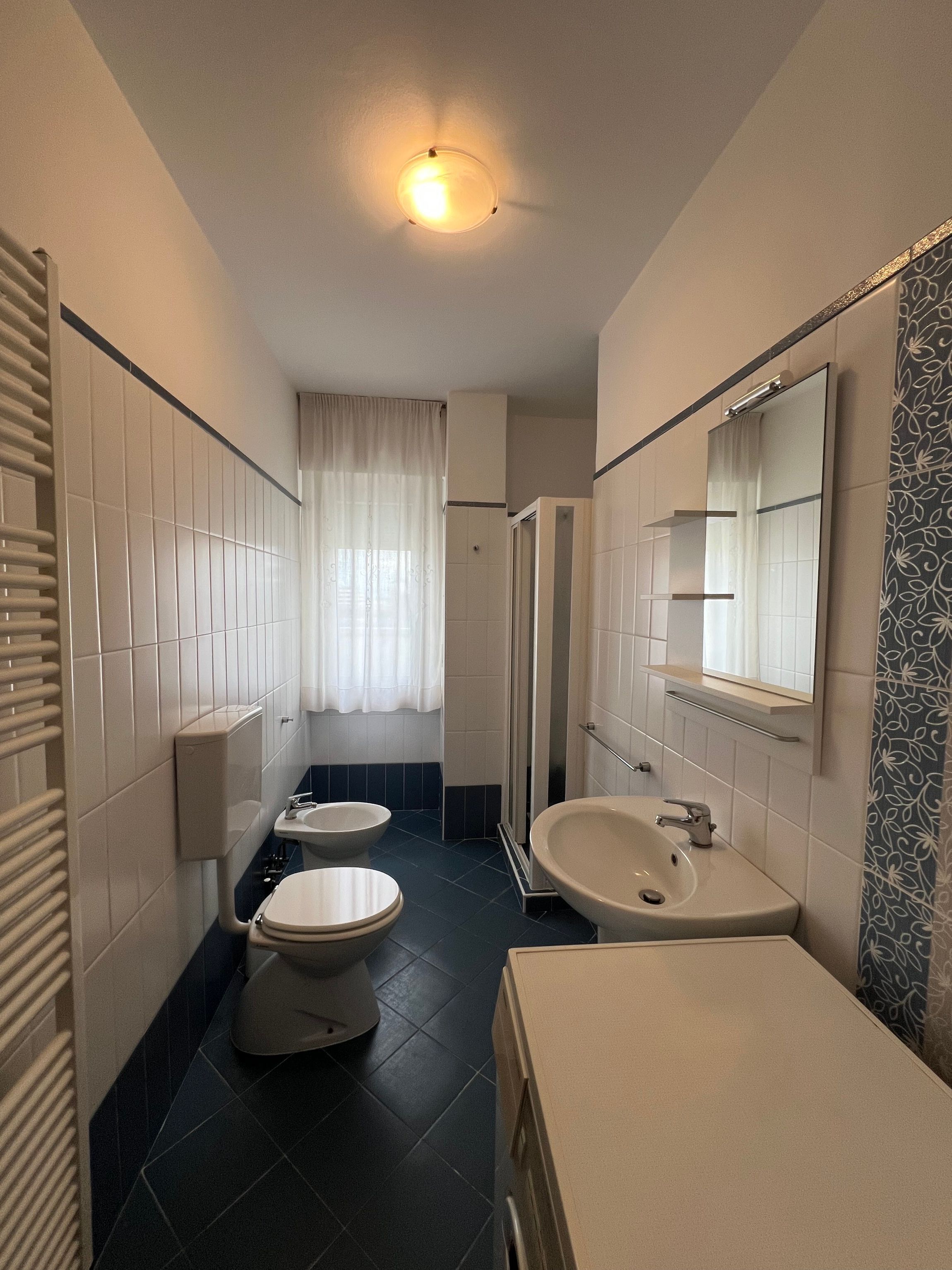 A bathroom with a toilet, bidet, sink, and a shower stall.