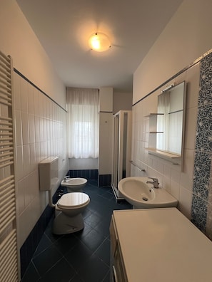 A bathroom with a toilet, bidet, sink, and a shower stall. - Lignano Beachfront Apartment (Lignano Sabbiadoro)