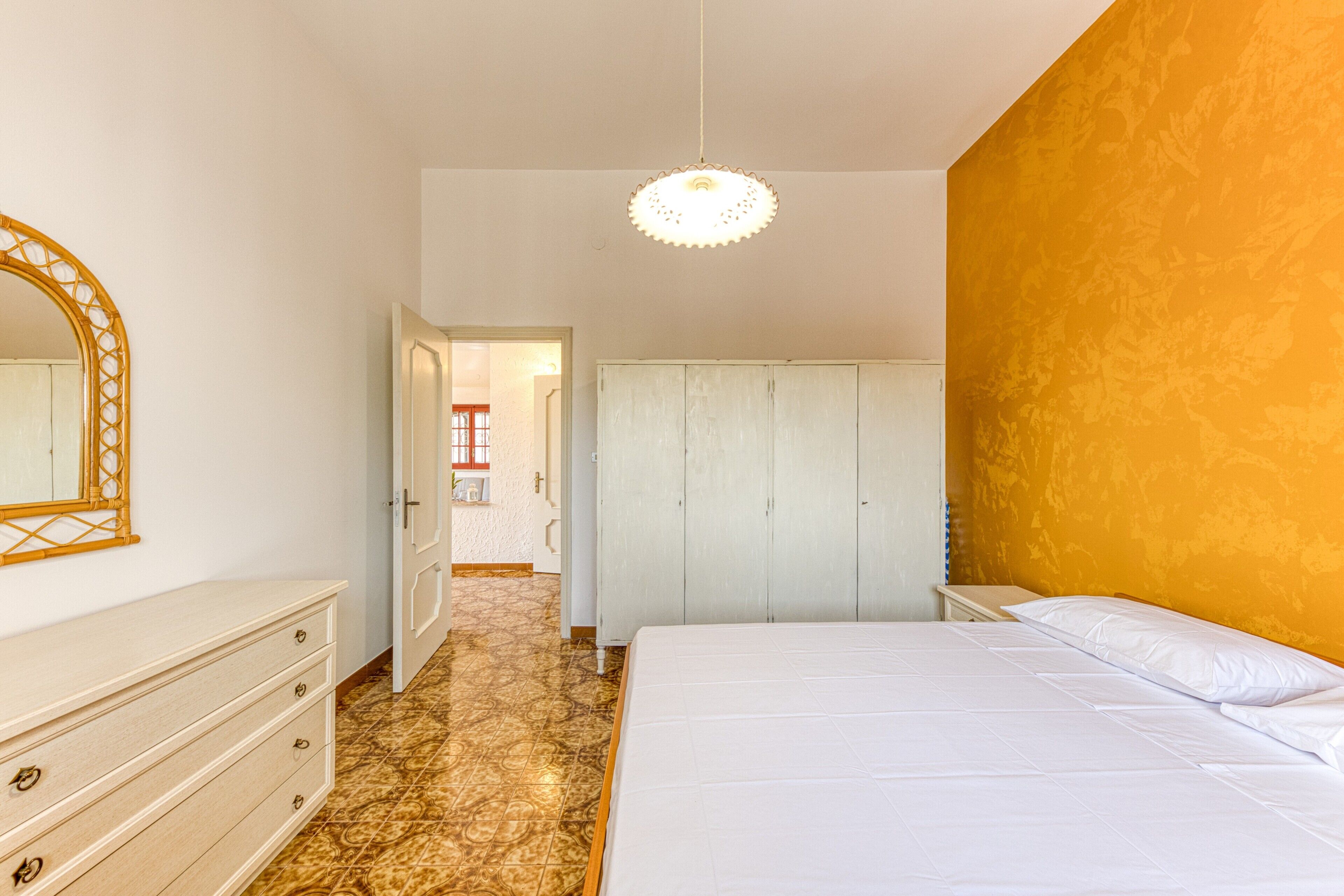 Un dormitorio con cama, cómoda, armario y espejo.