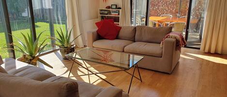 A spacious living room with a sofa, a glass coffee table, and a bookshelf.