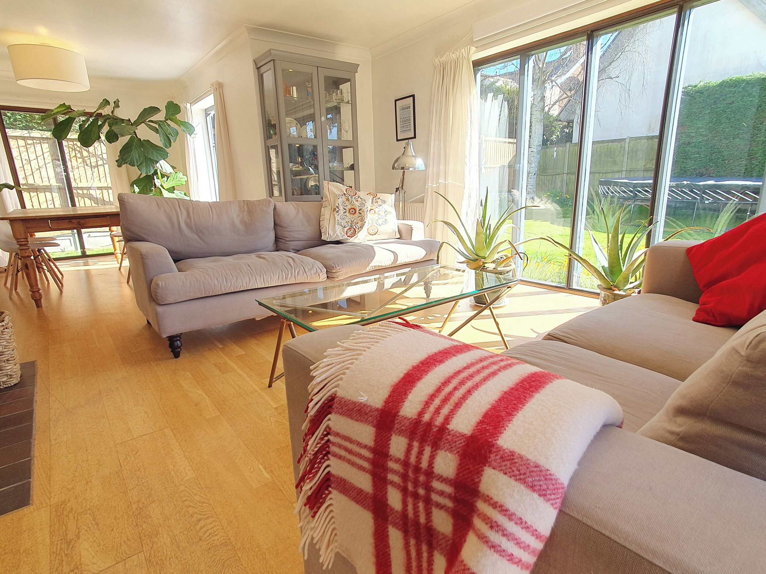 A living room with a sofa, a glass coffee table, a dining table, and a cabinet.