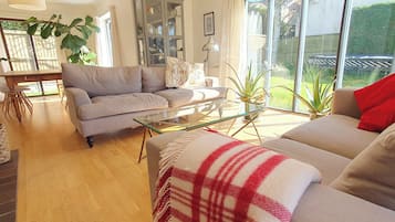 A living room with a sofa, a glass coffee table, a dining table, and a cabinet.