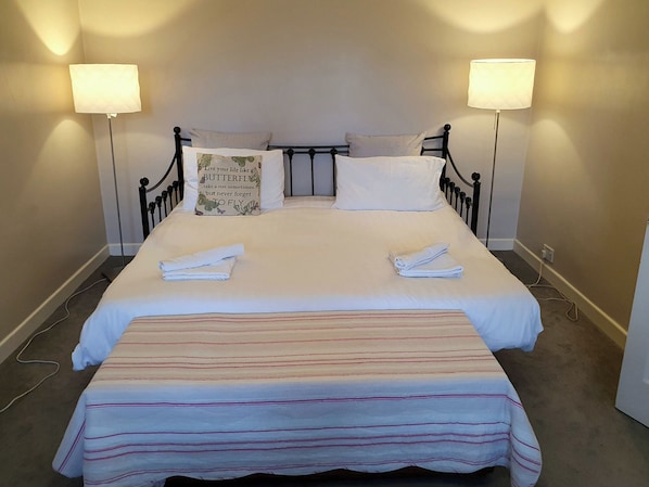 A neatly made bed with pillows, a bedside lamp, and a folded towel on the bed. - Island Retreat (Colchester)
