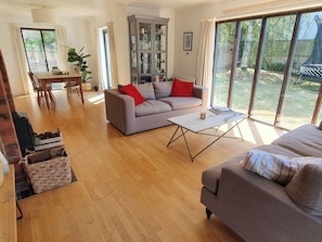 A spacious living room with a grey sofa, a coffee table, and a dining area with a table and chairs. - Island Retreat (Colchester)