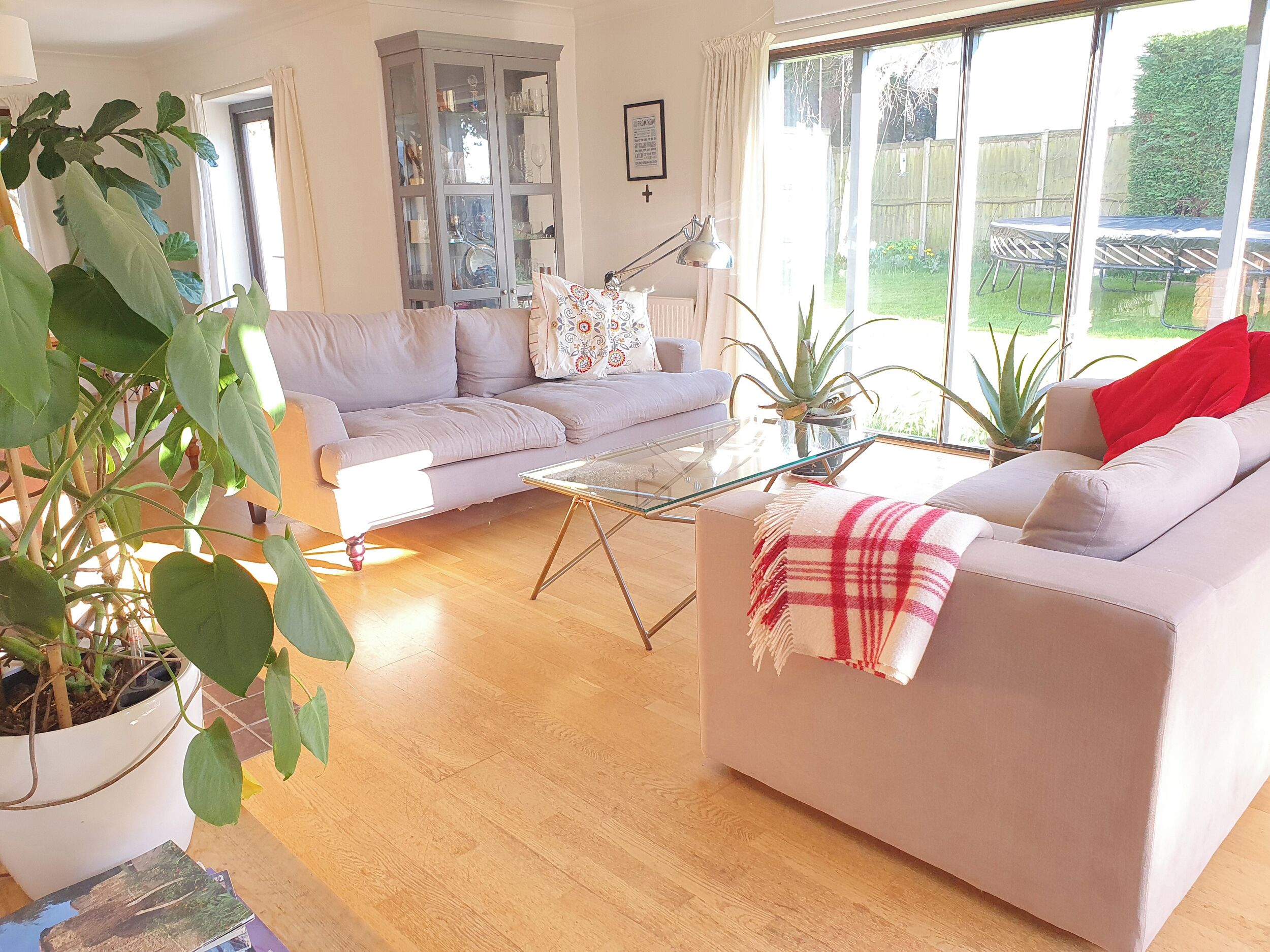 A living room with a sofa, a glass coffee table, a cabinet, and a large window.