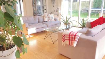 A living room with a sofa, a glass coffee table, a cabinet, and a large window.