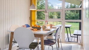 Uma sala de jantar com mesa, cadeiras e vista para o exterior.