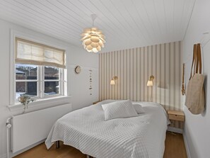 A bedroom with a bed, a window with curtains, a radiator, a wall-mounted clock, and a hanging bag. - "Etje" - 650m from the sea by Interhome (Skagen)