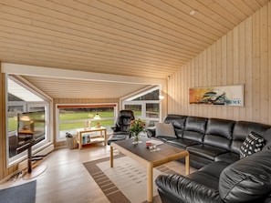 Ein modernes Wohnzimmer mit einer Ledersofa, einem Couchtisch und einem Fernseher.