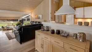 Een moderne keuken met houten kasten, een zwarte leren bank en een eethoek met uitzicht op de omgeving.