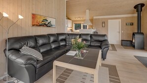 Een moderne woonkamer met een leren bank in zwart, een houten salontafel en een groot schilderij aan de muur.