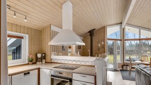 Een moderne keuken met houten lambrisering, een groot raam en een eetgedeelte met uitzicht.