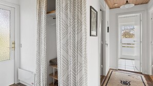 A hallway with a radiator, a door with a window, and a patterned curtain.